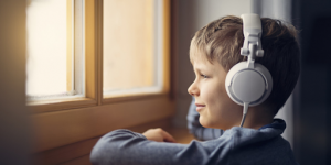 Un jeune enfant, casque à l’oreille, en train d'écouter de la musique