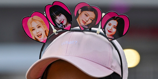 Un fan de musique K-pop portant une casquette où il y a la photo de chaque fille du groupe BlackPink
