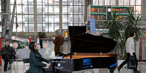 Une femme en train de jouer à un piano en libre-service dans une gare