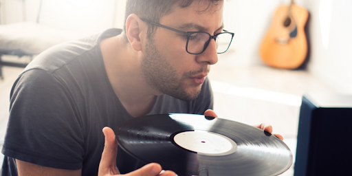 Un homme en train de nettoyer un disque vinyle avant de l'écouter