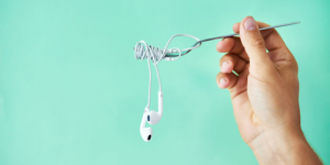 Une main tenant par une fourchette des écouteurs audio
