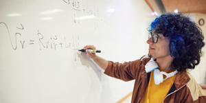 Un élève portant des casques en train de faire un exercice de mathématiques au tableau