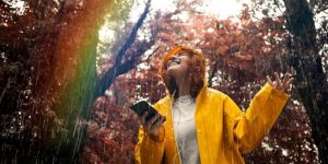 Une jeune femme écoutant de la musique sur son smartphone sous la pluie