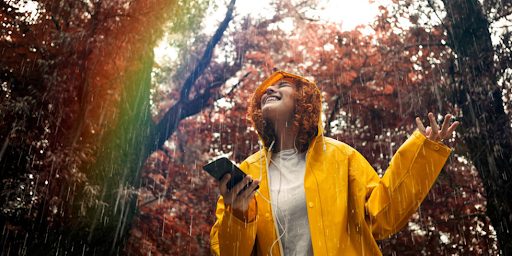 Une jeune femme écoutant de la musique sur son smartphone sous la pluie